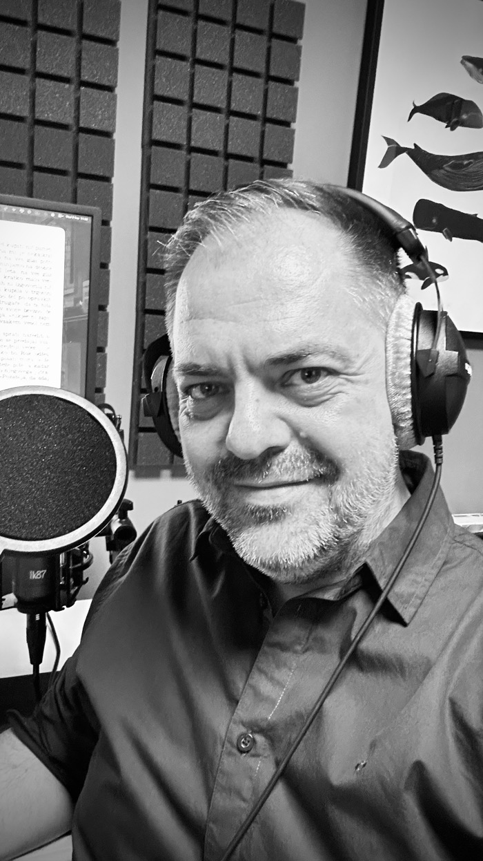 Peter recording in his home studio, wearing headphones at the microphone.